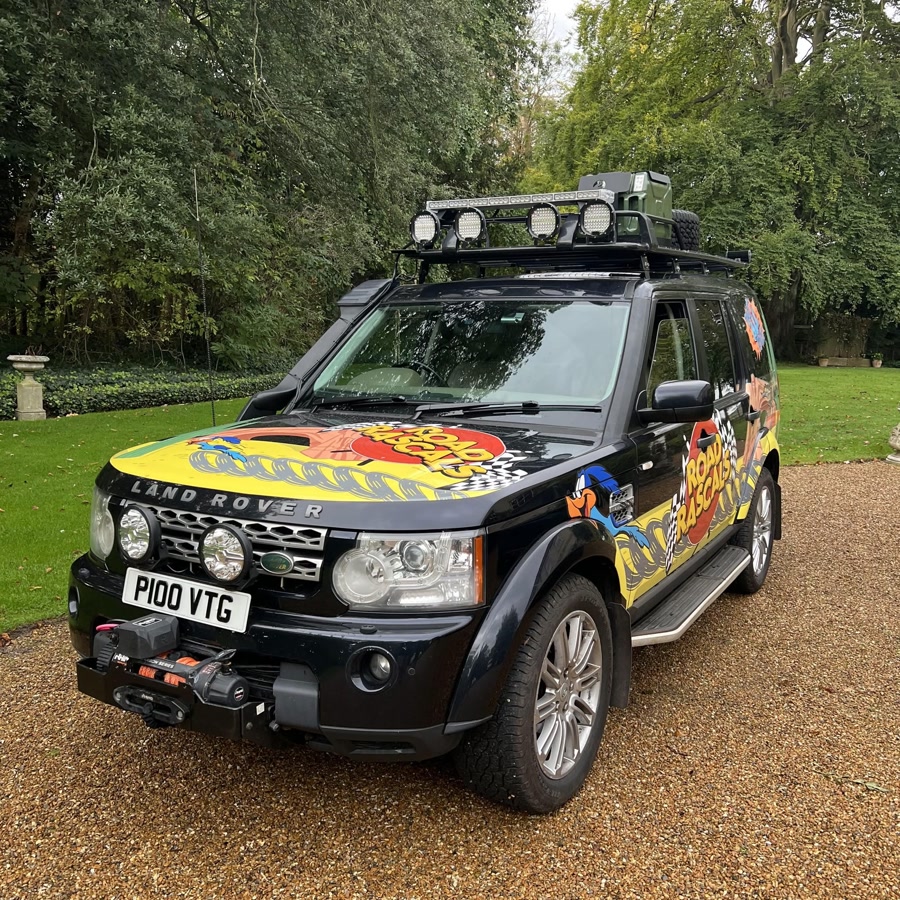 The Road Rascals Land Rover Discovery, kitted out with a roof rack and light bar, parked on a gravel driveway